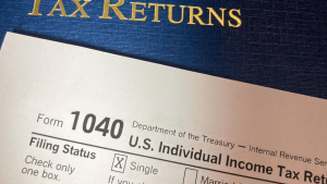 Close-up of IRS Form 1040 tax return with bold '1040' and 'U.S. Individual Income Tax Return' text; 'Tax Returns' title in the background.